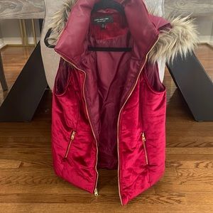 Red velvet vest with faux leather collar and fur trimmed hood. Gold zipper.